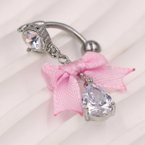 Detalle macro de piercing de ombligo plateado con lazo rosa y circón en fondo blanco