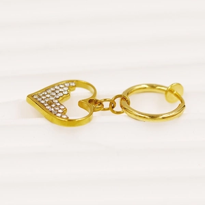 Nahaufnahme eines goldenen herzförmigen Bauchnabelrings mit weißen Strasssteinen und Politur