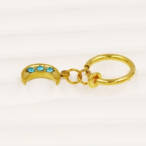 Detail eines goldenen Mondsichelnabelrings mit blauen Steinen auf weißem Untergrund