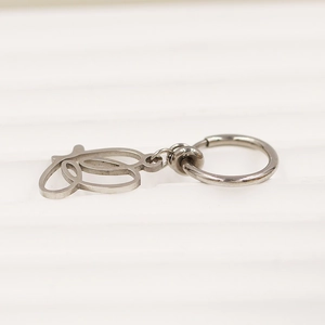 Detail eines silbernen Federclip-Bauchnabelrings mit hohlem geometrischem Anhänger