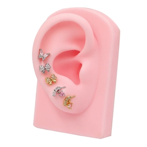 Detalle de pendiente con forma de pistola y un delicado colgante de corazón de circón rosa