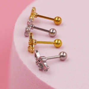 Primer plano de aretes de corona y mariposa con circonitas rosas en oro y plata