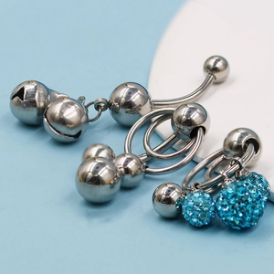 Detalle de piercings de ombligo de acero inoxidable con colgante de campana y cristal