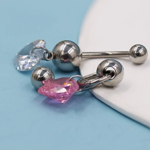Κοντινό πλάνο από ατσάλινο piercing ομφαλού με διαφανή και ροζ κρύσταλλα σε σχήμα καρδιάς