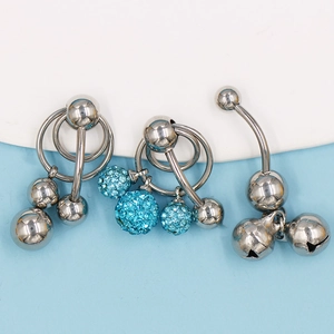 Vista detallada de piercings de ombligo con esferas, cristales azules y cascabeles