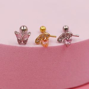 Detalle macro de colgantes de mariposa y corazón con circonita rosa en aretes de piercing