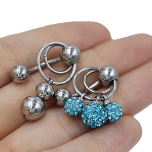 Detalle de piercings para ombligo de acero con bolas pulidas y colgantes de cristal azul