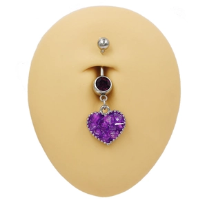Detalle macro de un piercing de ombligo plateado con colgante de corazón lila en modelo
