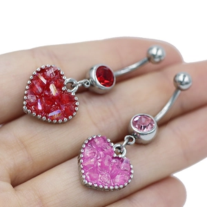 Vista detallada de piercings de ombligo de corazón con cristales rosas y rojos brillantes