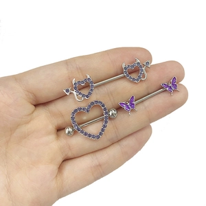 Detail van paarse hart- en vlinder tepelpiercings met ingelegde zirkonia steentjes