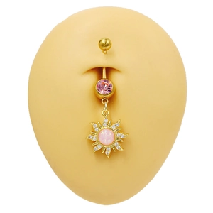 Détail d'un piercing de nombril doré avec pendentif tournesol en zircon rose sur modèle