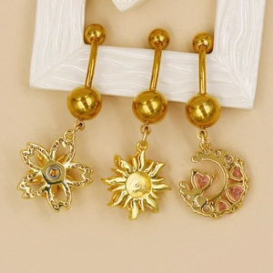 Détail de piercings de nombril dorés avec breloques soleil, fleur et lune et gemmes roses