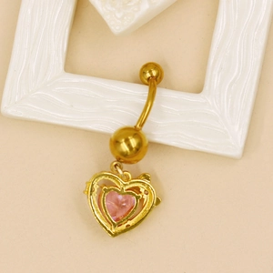 Détail macro du piercing de nombril doré avec pendentif en zircone en forme de cœur rose