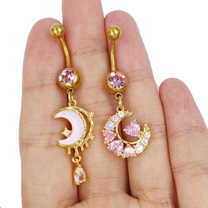 Gros plan de piercings de nombril lune dorée avec cristaux roses en cœur et goutte