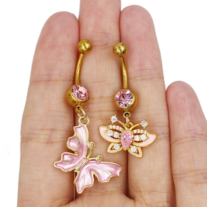 Détails de piercings de nombril papillon avec émail rose et cristaux sur une paume