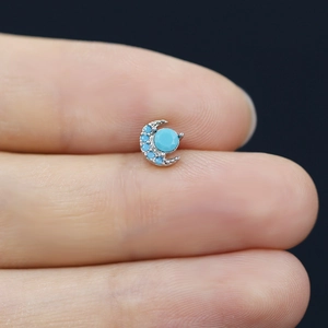 Detailed close-up of a crescent moon nose stud featuring turquoise stones in silver metal