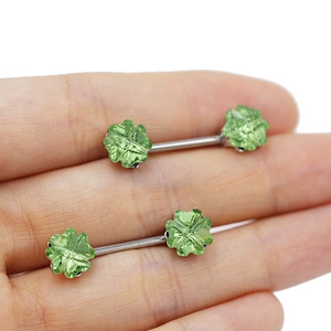 Close-up of green clover crystal nipple rings with silver stainless steel straight bars