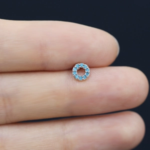 Macro view of a delicate silver nose stud featuring sky blue zircon in a micro-pave setting