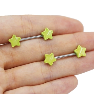 Detail of silver piercing bars with green five-point stars held by hand close-up