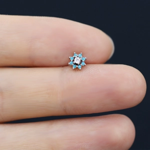 Detail shot of a flower-shaped nose stud with blue beads and a clear zircon center
