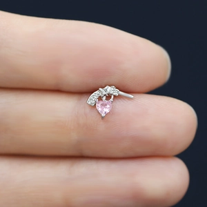 Macro detail of silver gun earring with a sparkling pink heart-shaped zircon drop