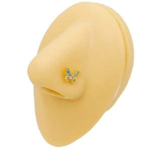 Detailed view of a gold butterfly nose stud with pink and blue crystals on a silicone model