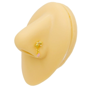 Macro detail of golden star nose stud with dangling pink teardrop zircon on a model
