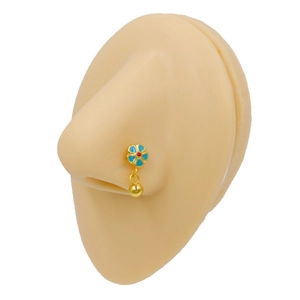 Dettaglio di un piercing al naso boho dorato con fiore blu e ciondolo a sfera mobile