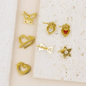 Dettaglio del set di piercing al naso dorati con farfalla, cuore e corona con pietre rosse