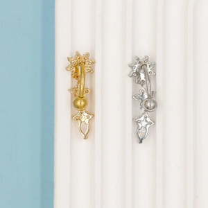 Macro detail van goud en zilver navelpiercings met zirkoon ster en druppel hangers