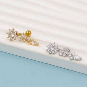 Detail van bloem navelpiercings in goud en zilver met fonkelende zirkonia kristallen