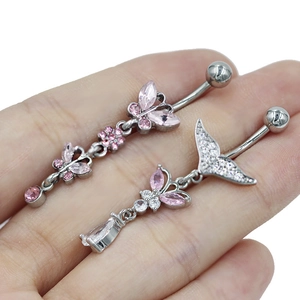 Detailopname van navelpiercings met roze vlinders en bloemvormige kristallen hangers