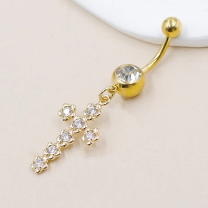 Detailed view of a gold cross belly button ring with sparkling zircon stones
