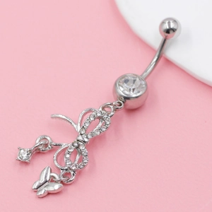 Macro detail of stainless steel belly ring featuring sparkling crystal bow and butterfly pendant