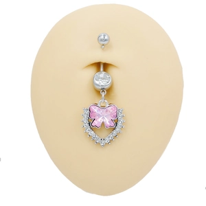 Primer plano de piercing de ombligo con lazo rosa y corazón de circón en modelo de silicona