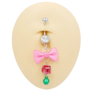 Macro shot of belly ring with pink bow and green bell on silicone model skin