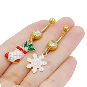 Detalle de piercings de ombligo con colgantes de calcetín navideño rojo y copo de nieve
