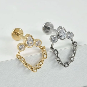Macro detail of G23 titanium labret studs with pear-shaped zircon and hanging chain accents