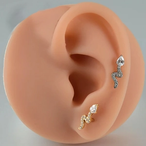 Macro shot of silver and gold snake stud earrings with zircon inlay on model