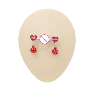 Macro detail of red heart-shaped nipple ring with small bells and engraved lettering