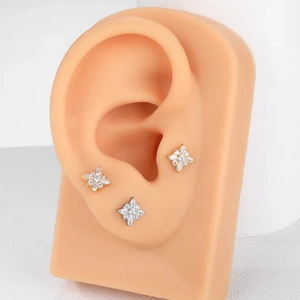 Detalle de pendientes de titanio G23 con estrellas de circonita en modelo de oreja