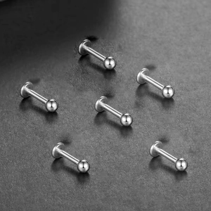 Platte zilveren titanium labret studs met gepolijst bolletje op donkere textuur
