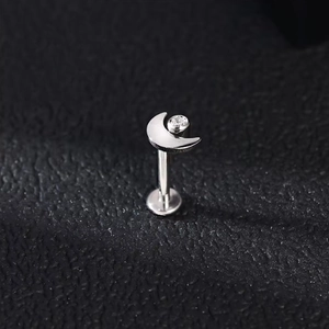 Detalle de piercing labret luna de titanio G23 con circón claro sobre cuero negro denso