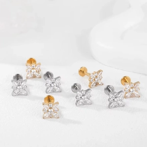 Detalle macro de piercings labret de titanio G23 con flores de circonita marquise