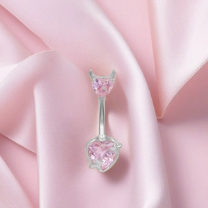 Pink heart navel ring with devil horns and tail on soft pink satin background