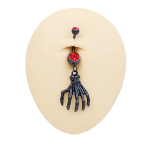 Vista macro de piercing de ombligo gótico mano de calavera con circón corazón rojo