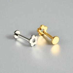 Détail des piercings labret en titane en forme de fleur, finitions or et argent