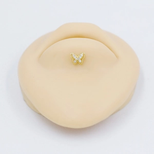 Elegant gold butterfly lip piercing stud with white zircon crystals on silicone skin model