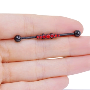 Vue détaillée d'un piercing industriel noir orné de cinq pierres précieuses rouges