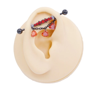Black industrial barbell with red rhinestones and hanging heart-shaped gems on ear model